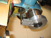 The caliper passes through a void in the millhead casting.  The beam is fixed to an arm on the quill collar.  The reading head is held stationary.  From this bottom view, you can see the caliper reading head and the quill gear.