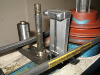 Four pieces of aluminum together form the top bracket, which clamps onto the small (depth-indicating) part of the caliper.  It appears crooked, and actually is, because the casting is very uneven where it mounts.