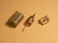 Disassembled brushed DC motor: casing (with permanent magnets), rotor (with coils), and brushes/contacts