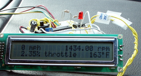 LCD display of the running OBD-II car computer interface, with the NerdKits electronics kit in the background