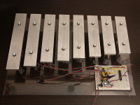 The xylophone is mounted on a transparent acylic sheet.