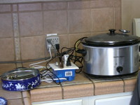 The display/control box, servo-actuated dimmer box, and slow cooker sit side-by-side on the kitchen counter.