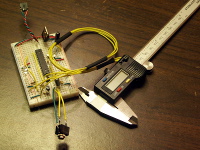 The calipers are connected via 4 wires to the solderless breadboard containing the NerdKits microcontroller setup.