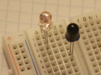 Unlike typical LEDs and phototransistors, the flattened edge of the plastic T1-3/4 body here corresponds to the longer lead (but on most parts it is usually the shorter lead). The LED anode is in breadboard row 2, and cathode is in row 3. The phototransistor collector is in row 5, and the emitter is in row 6.